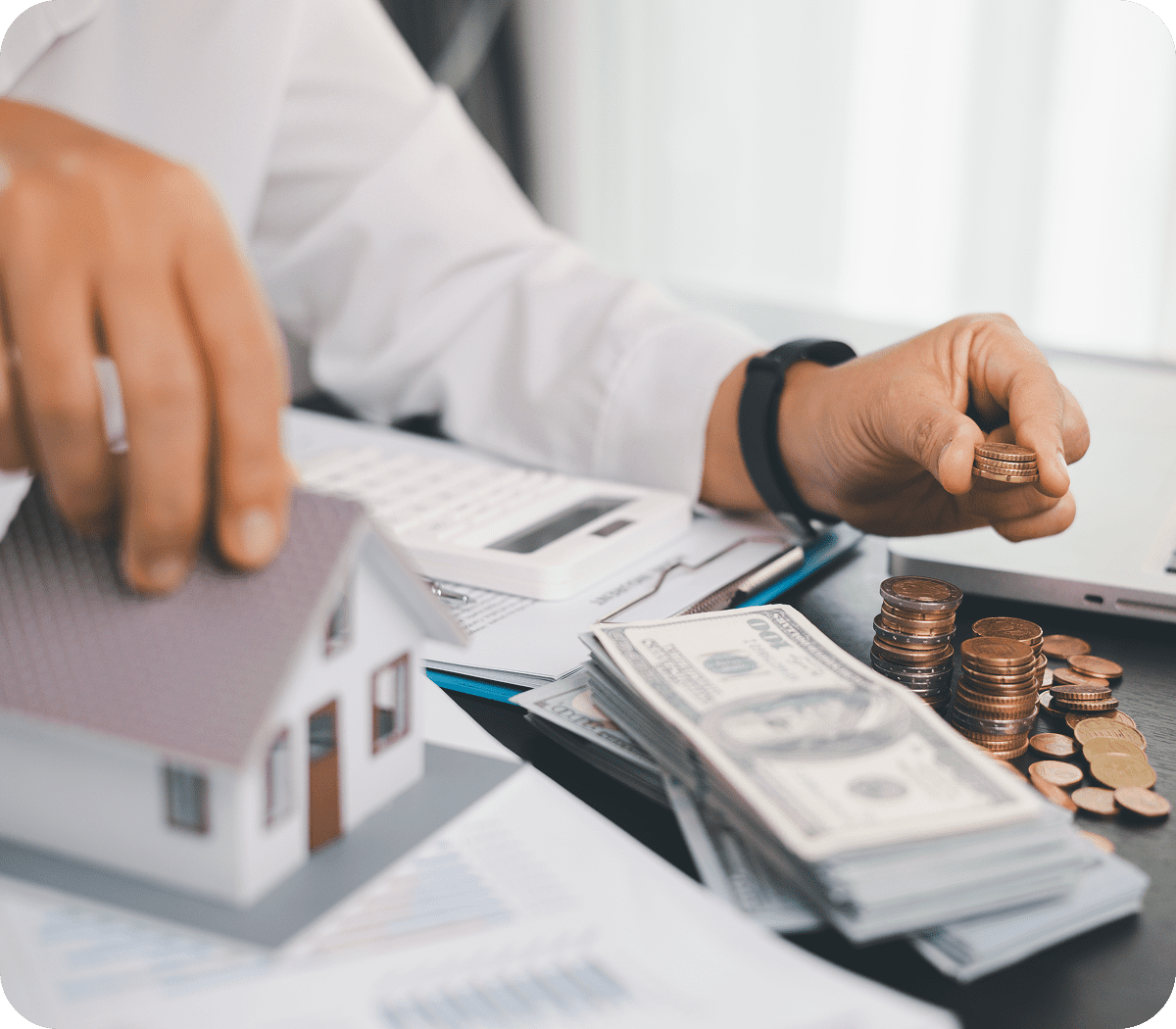 Hands with cash, coins, and house model.
