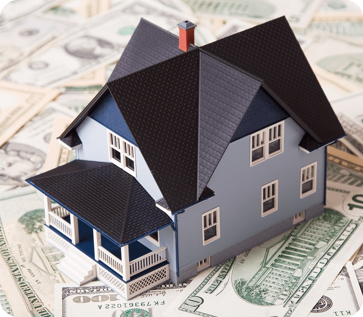 Model house on scattered dollar bills.