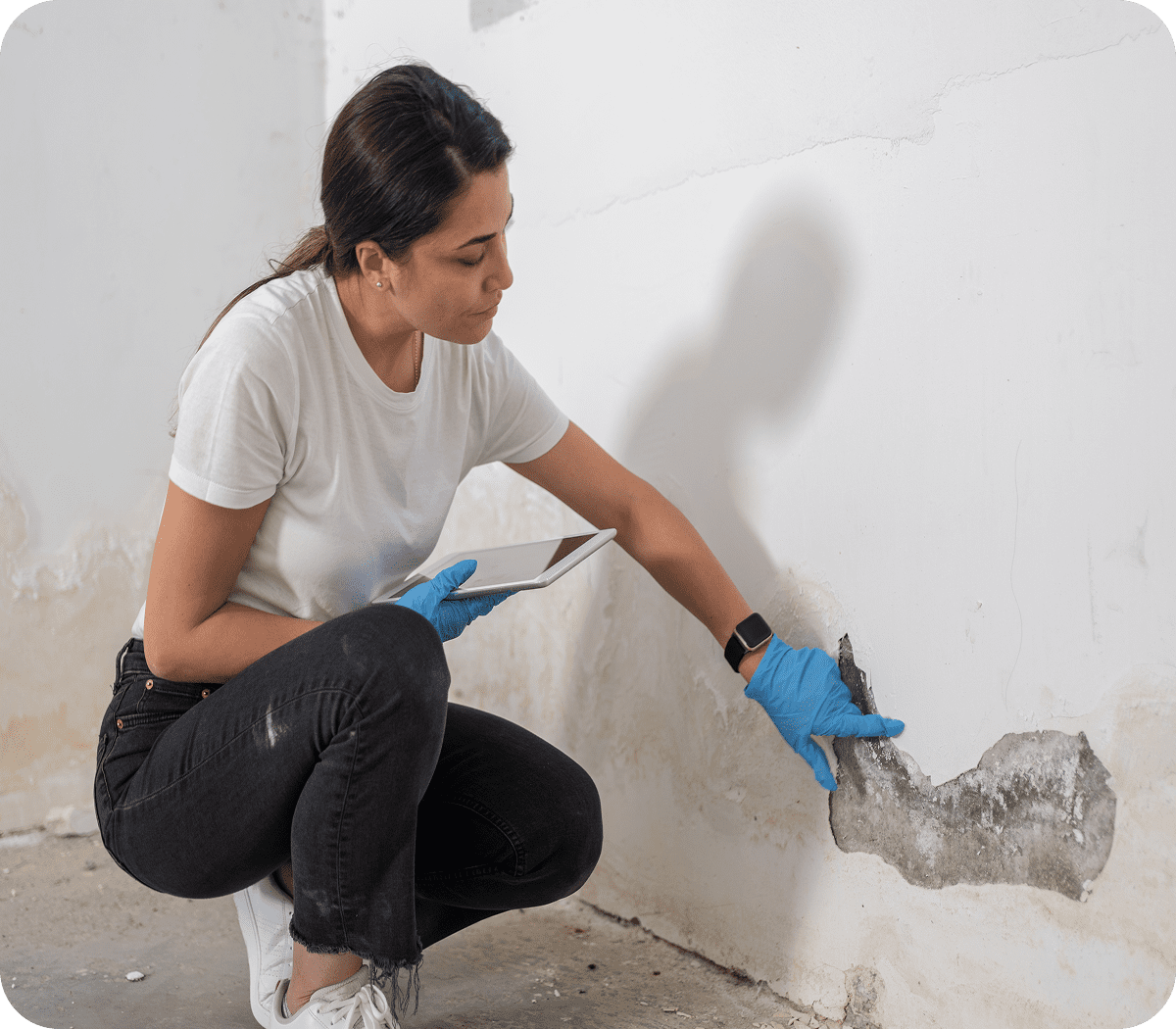 Person inspecting wall damage with tablet.