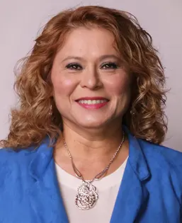 Smiling woman with curly hair, blue blazer.