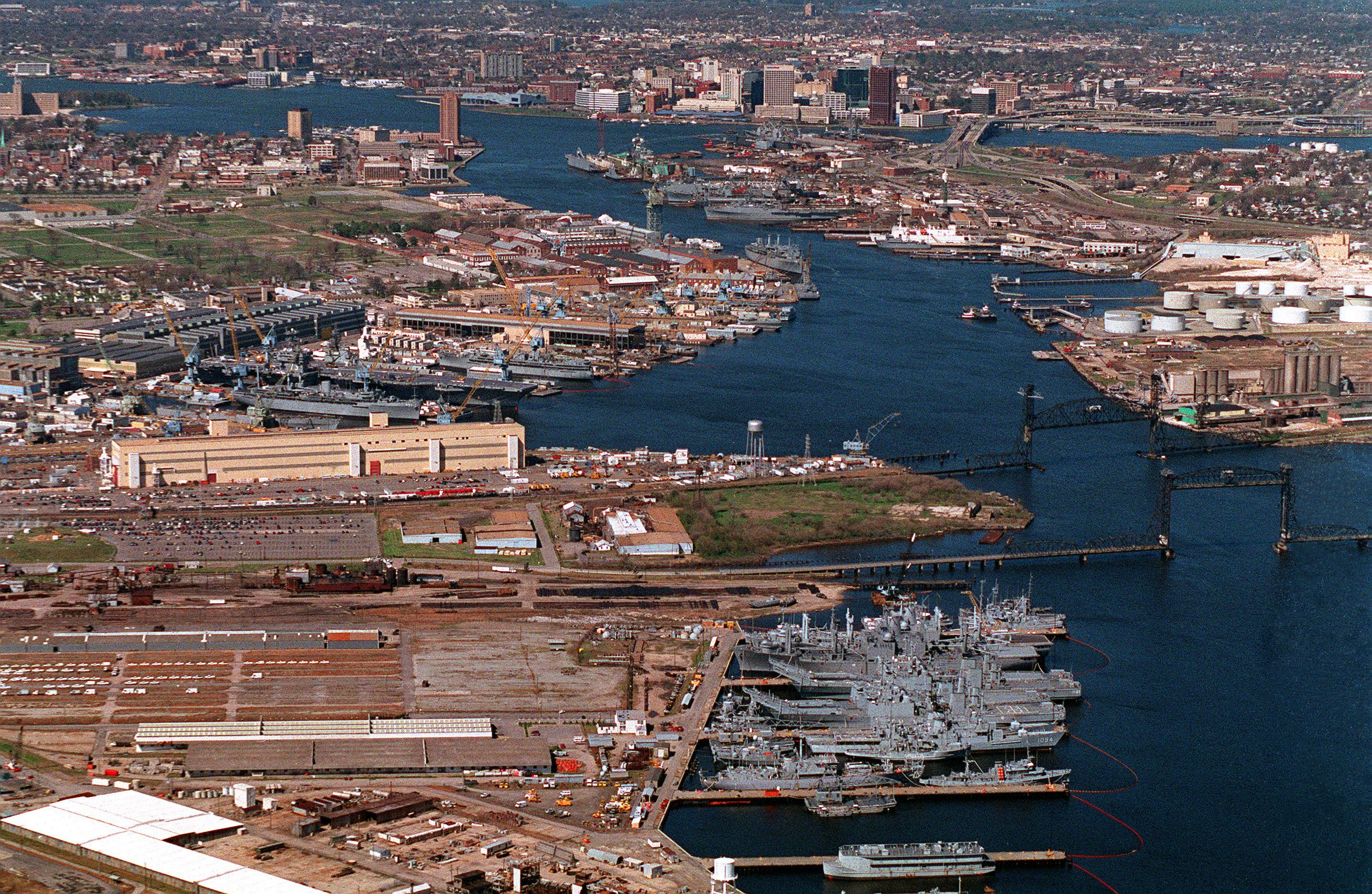 An aerial view of the Norfolk Naval Shipyard located on the Elizabeth River.   At the bottom right is the South Gate Annex where ships of the mothball fleet are stored.  At left center is the main shipyard.  Futher back on the righthand side of the river is the Norfolk Shipbuilding &amp; Drydock Company (NORSHIPCO).  The city of Norfolk is in the background.